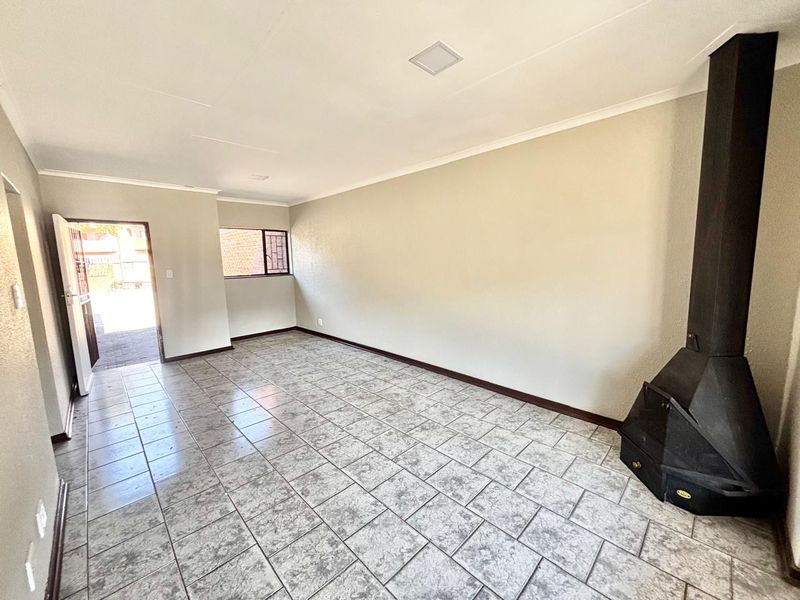 Spacious, empty living area featuring tiled flooring, a built-in fireplace, and direct access to the exterior through a security gate.