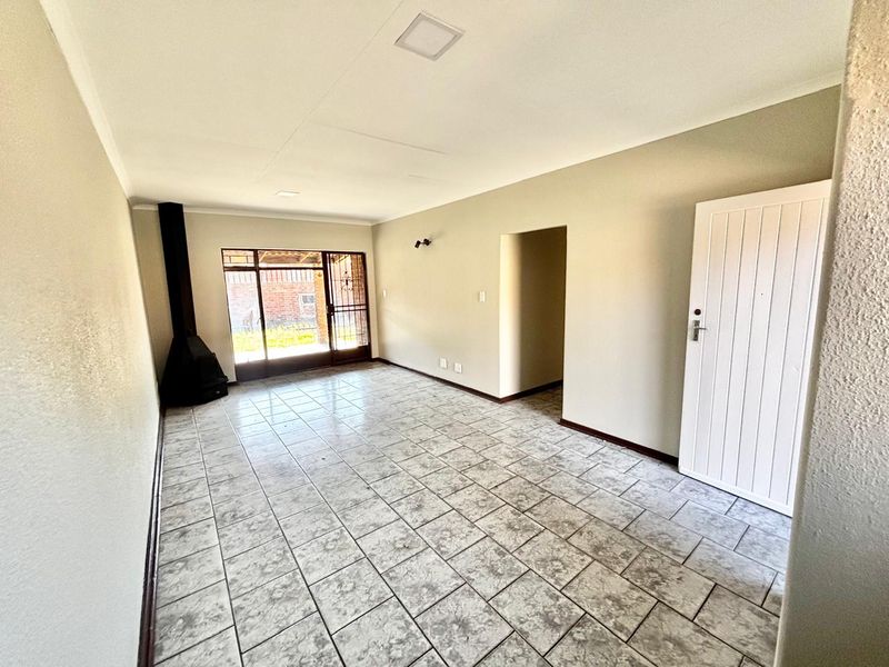Spacious living area featuring neutral tiled flooring, a freestanding fireplace, and direct access to the outdoor area through a sliding glass door.