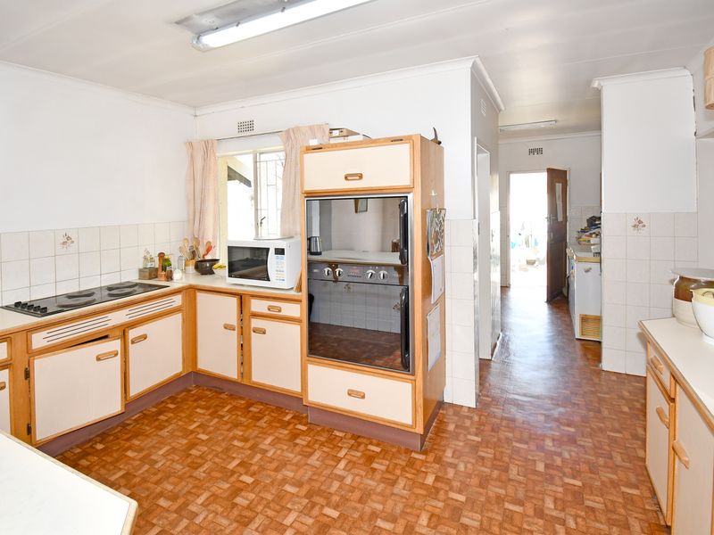 A functional kitchen featuring built-in oven, electric hob, and tiled splashbacks, offering a dated aesthetic ready for modern renovation.