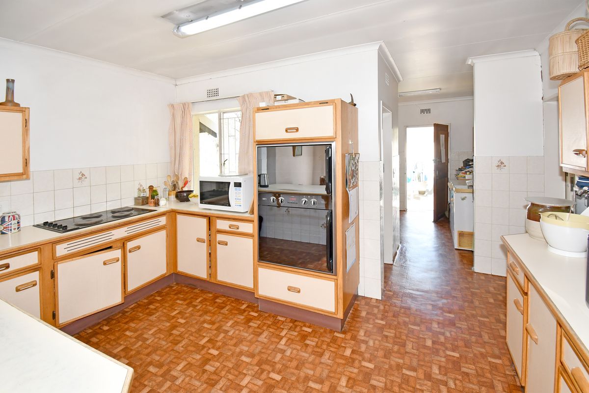 A functional kitchen featuring built-in oven, electric hob, and tiled splashbacks, offering a dated aesthetic ready for modern renovation.