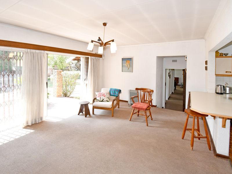 Open plan living and kitchen area featuring a breakfast bar, carpeted flooring, and large sliding doors providing access to the outdoor patio.