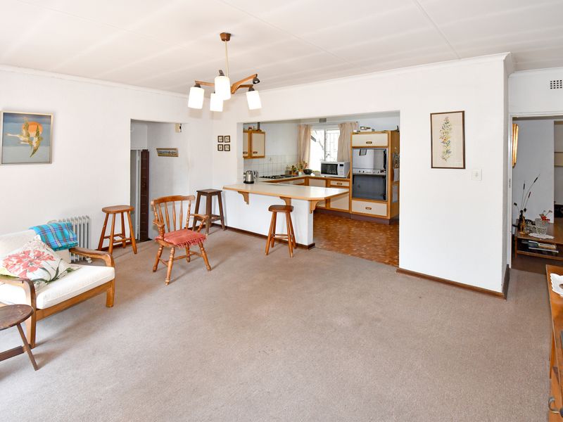 Open plan living and kitchen area featuring a breakfast bar, built-in oven, and cabinetry, with a combination of carpet and vinyl flooring.