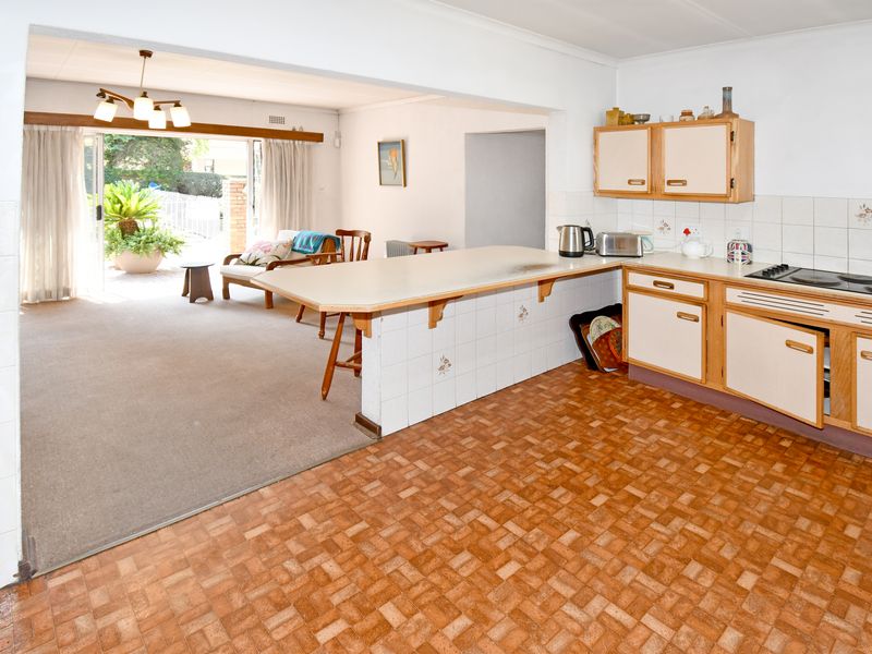 Open plan kitchen and living area featuring a breakfast bar, tiled backsplash, and sliding doors leading to an outdoor patio space.