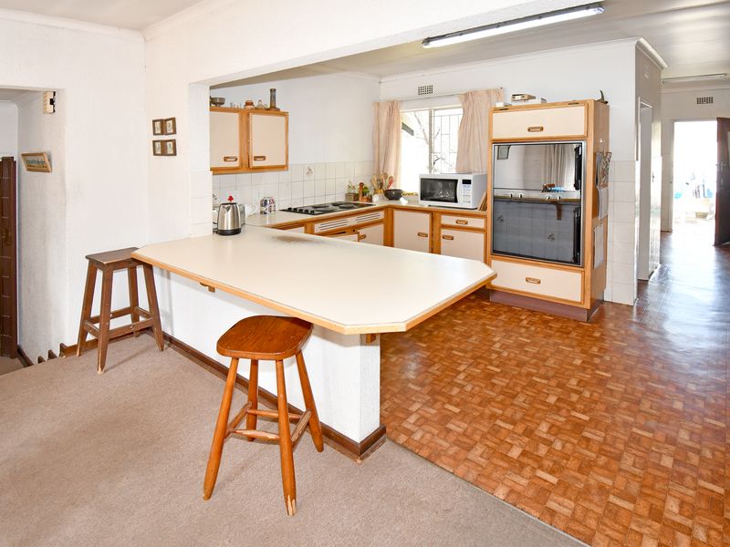 A dated kitchen featuring built-in cabinetry, a breakfast bar, and integrated oven, offering potential for a modern renovation.