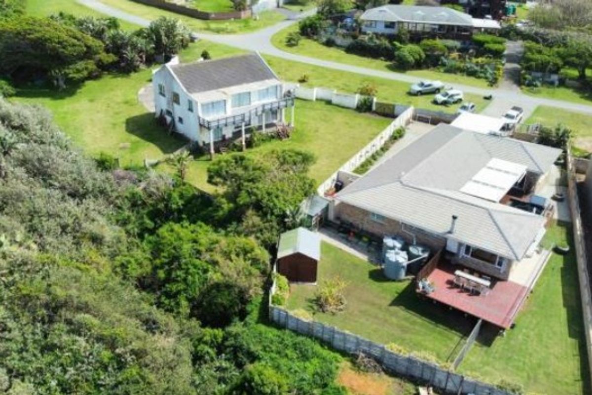 Aerial view of a residential property featuring a tiled roof, timber deck, and surrounding garden area with perimeter fencing.