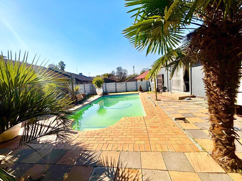 Outdoor pool area featuring a paved patio and perimeter wall, requiring maintenance to the pool water and paving surfaces.