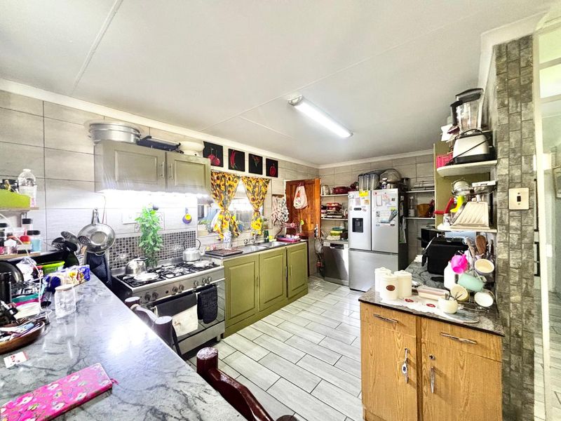 Functional kitchen featuring gas stove, extractor fan, stone countertops, and tiled flooring with ample built-in cabinetry for storage.