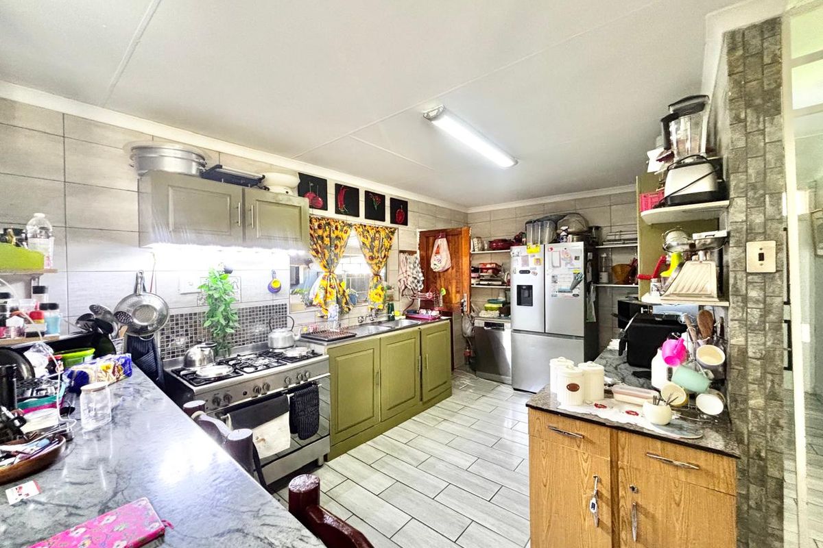 Functional kitchen featuring gas stove, extractor fan, stone countertops, and tiled flooring with ample built-in cabinetry for storage.