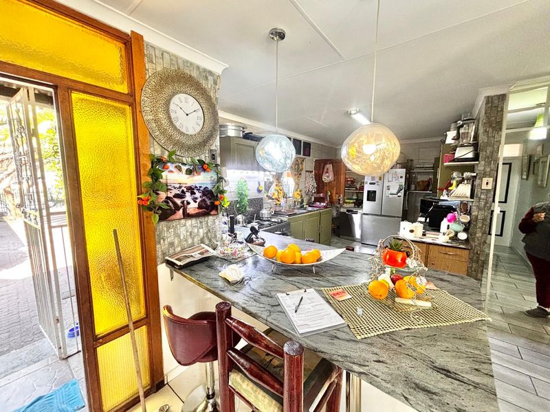 A functional kitchen featuring a stone breakfast bar, pendant lighting, and tiled flooring, with direct access to an exterior entrance.