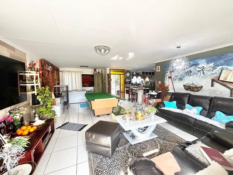Spacious open-plan living area featuring tiled flooring, integrated kitchen space with island, and versatile layout suitable for dining and entertainment.