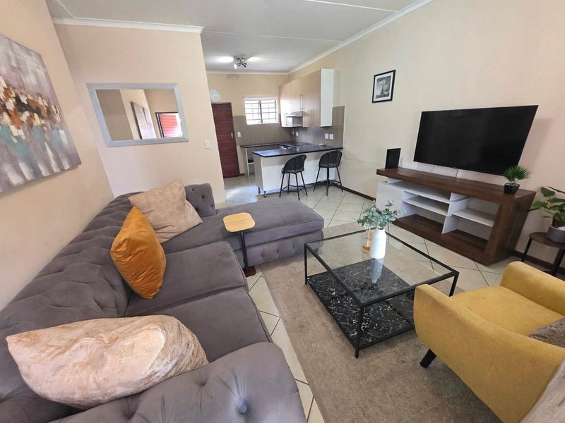 Open plan living area featuring a kitchen with breakfast bar, tiled flooring, and neutral wall finishes, creating a functional and connected living space.