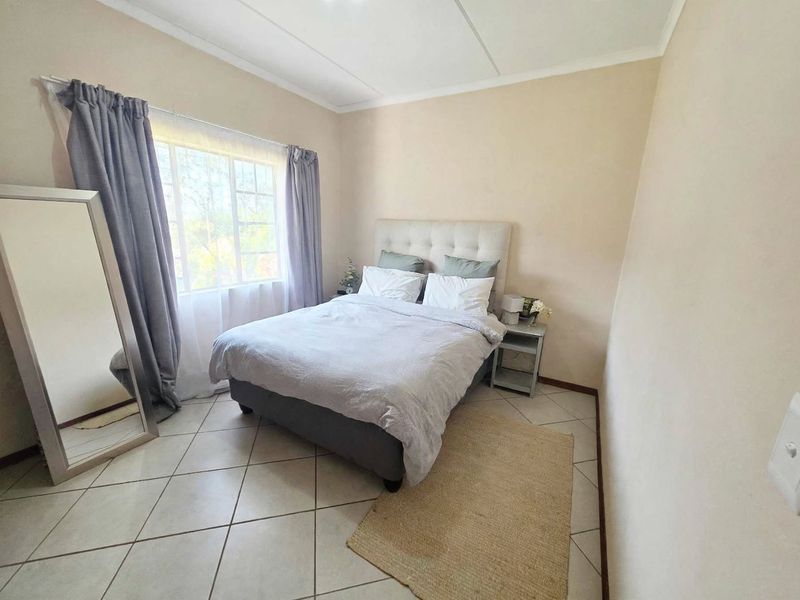 A functional bedroom featuring tiled flooring and a window, providing a neutral space ready for personalization.