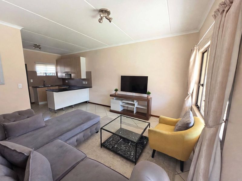 An open-plan living area featuring a functional kitchen with modern cabinetry, tiled flooring, and a seamless flow into the comfortable lounge space.