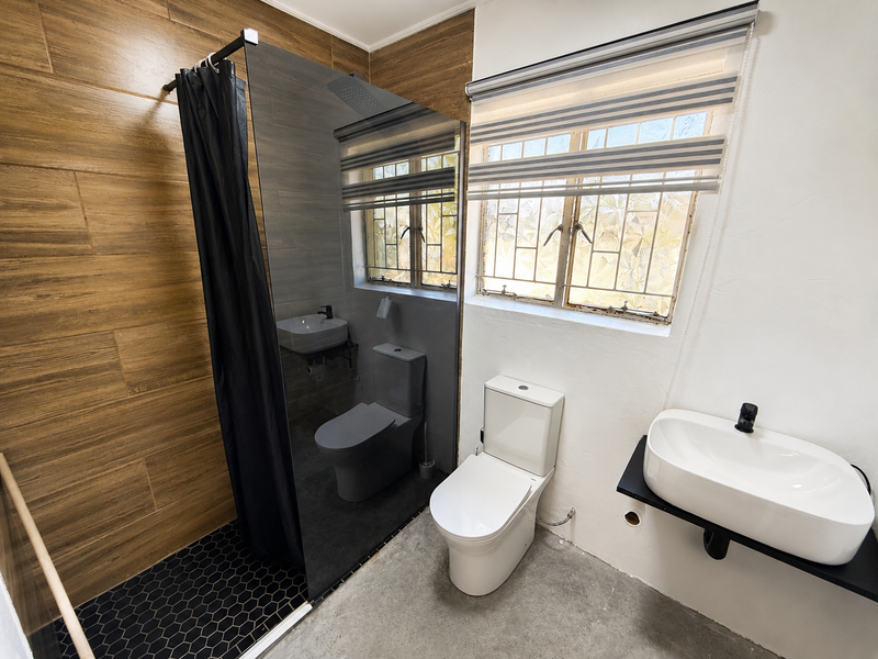 Modern bathroom featuring a walk-in shower with glass screen, wood-look wall tiling, hexagonal floor tiles, and a contemporary wall-mounted basin.
