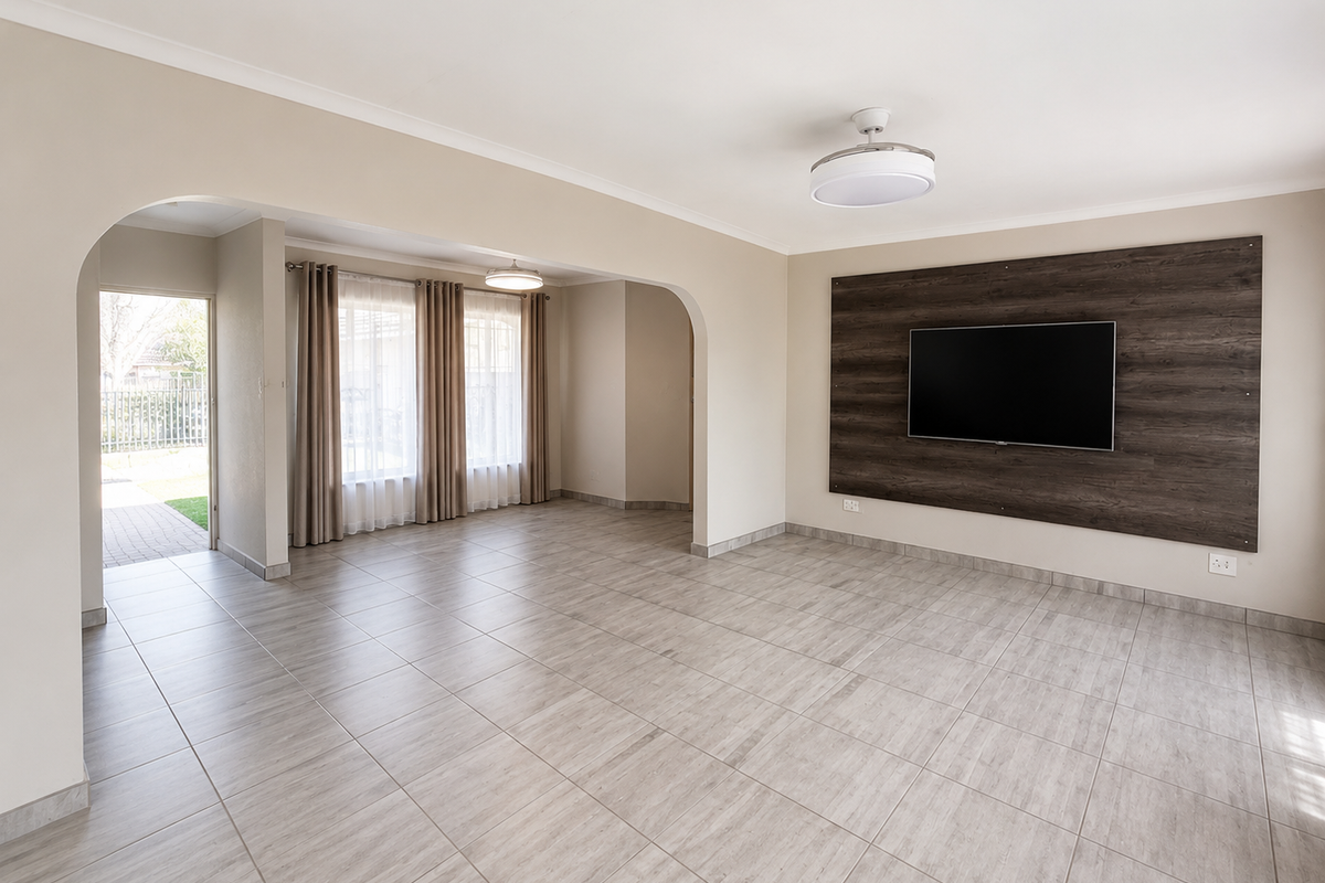 Spacious, light-filled living area featuring neutral tiled flooring, a decorative wood-look feature wall, and an open-plan layout with an arched transition to the entrance.