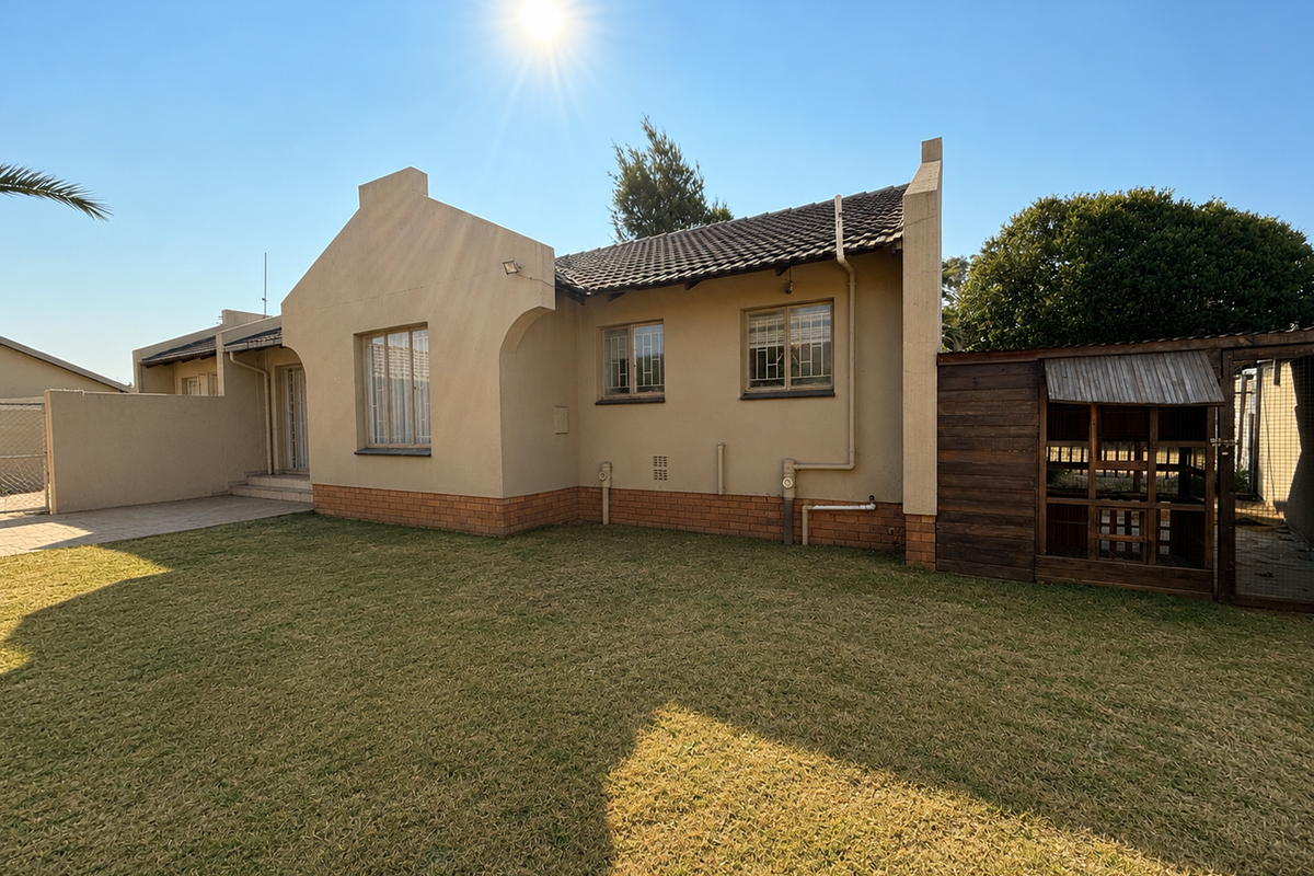 Rear view of the house featuring a paved patio area, well-maintained lawn, and secure window bars.