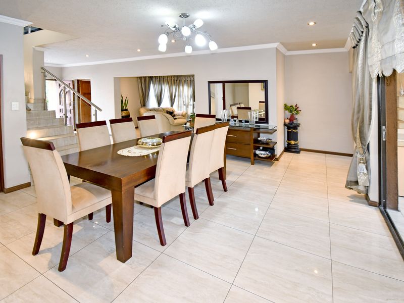 Spacious dining area featuring polished tile flooring, recessed lighting, and an open-plan layout with a staircase leading to the upper level.