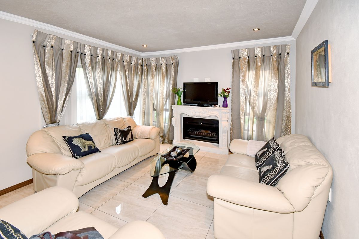 A comfortable living room featuring tiled flooring, a central fireplace, and recessed downlighting, creating a bright and inviting space.