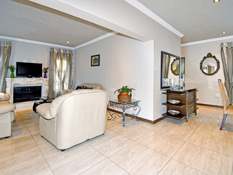 Spacious open-plan living area featuring neutral tiled flooring, recessed lighting, crown molding, and a decorative fireplace.