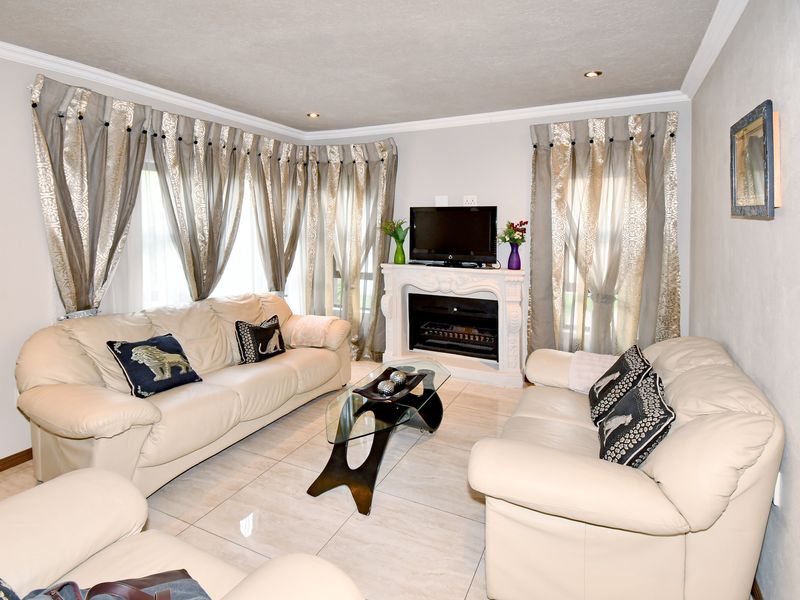 A comfortable living room featuring tiled flooring, a central fireplace, and recessed downlighting, creating a bright and inviting space.