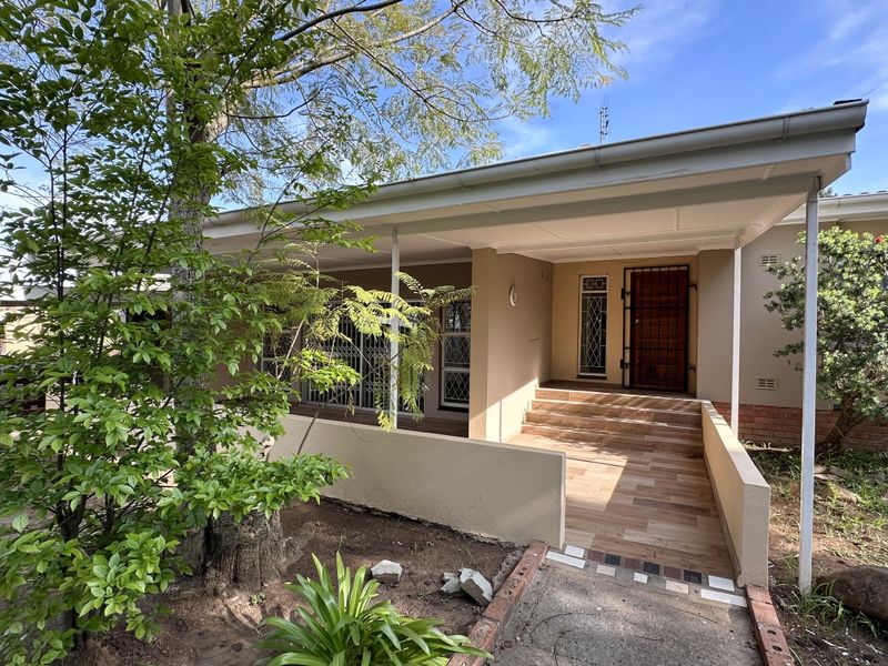 Front entrance of the house featuring a covered patio, tiled steps, and a secure metal entrance gate.