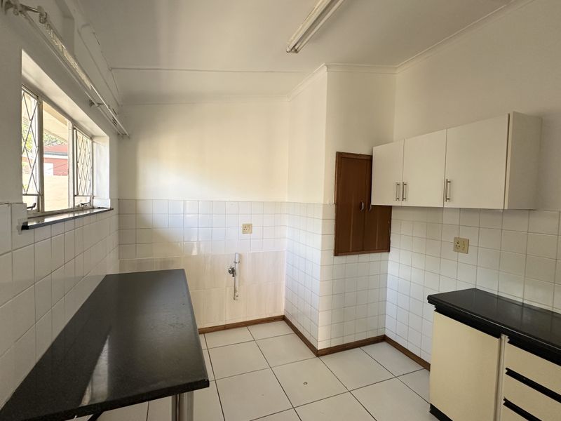 A functional scullery area featuring tiled splashbacks, built-in cabinetry, and durable countertops with dedicated plumbing connections for laundry or kitchen utility use.