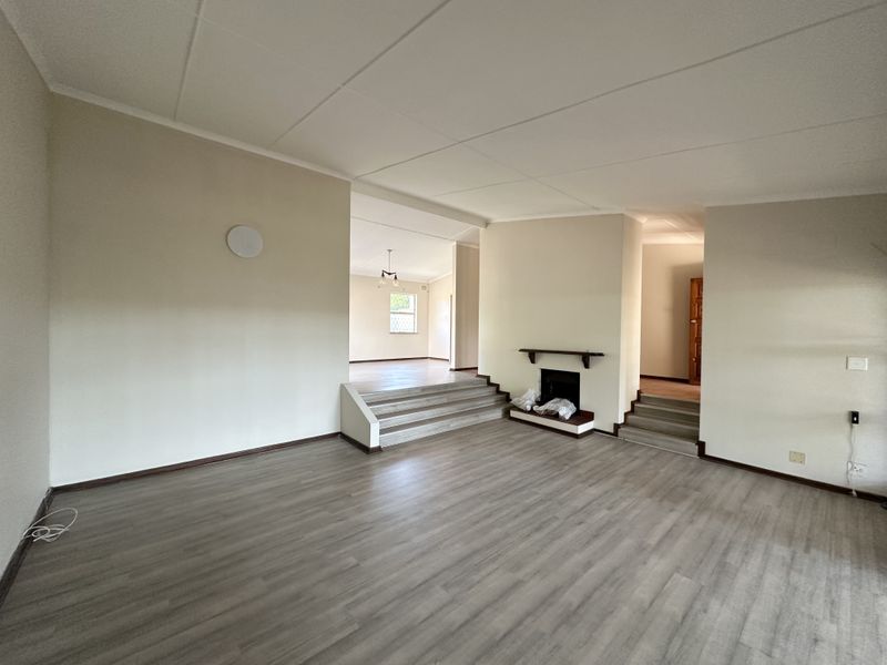 Spacious open-plan living area featuring split-level flooring, a built-in fireplace, and neutral finishes throughout, offering a versatile layout for modern living.