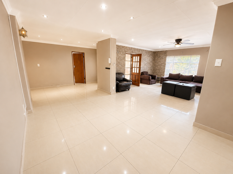 Spacious living area featuring polished tiled flooring, recessed downlighting, a ceiling fan, and a textured stone feature wall.