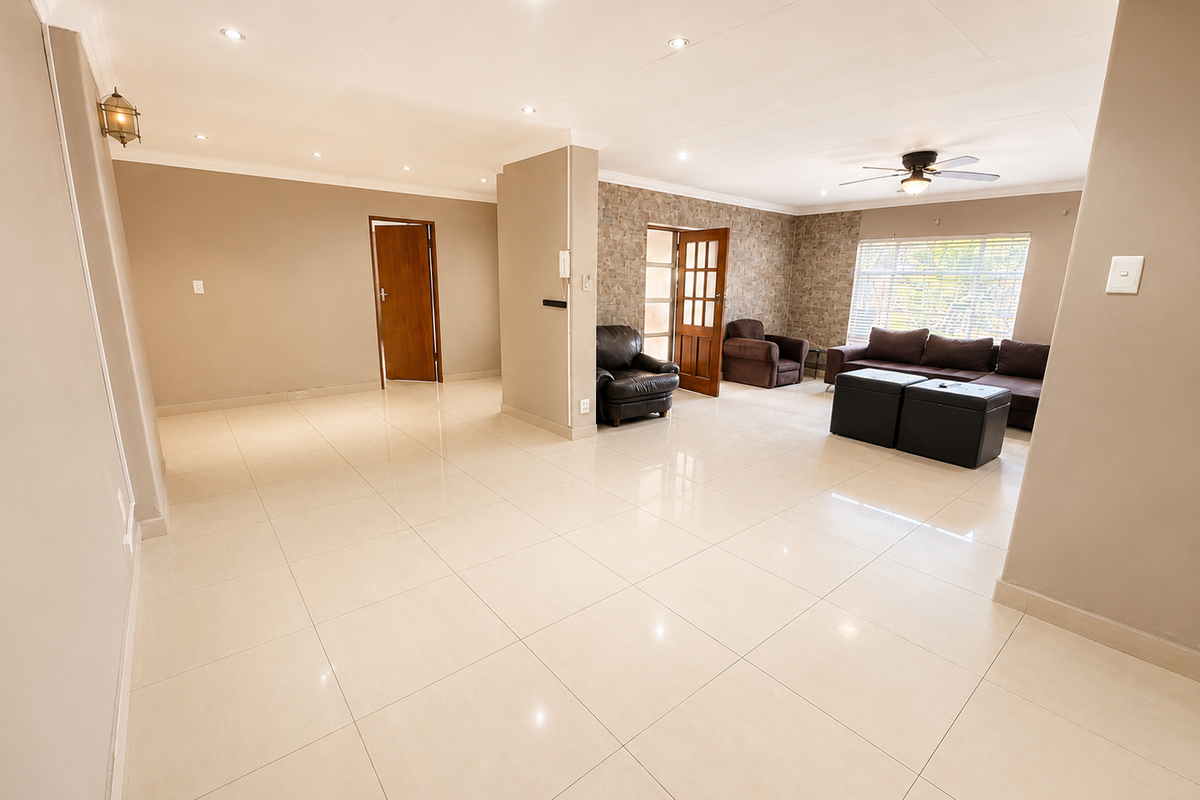 Spacious living area featuring polished tiled flooring, recessed downlighting, a ceiling fan, and a textured stone feature wall.