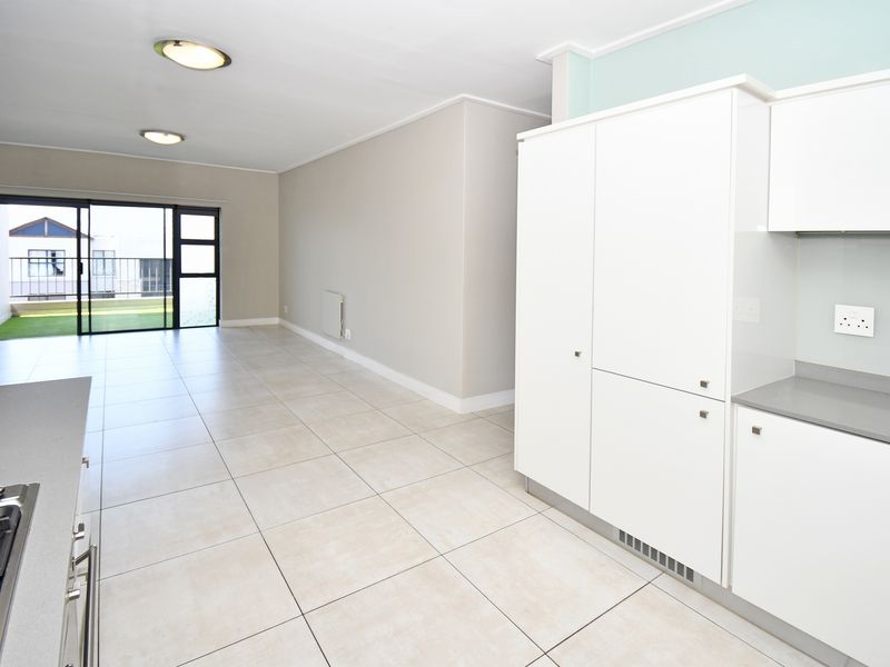Spacious open-plan living area featuring a modern kitchen with built-in cabinetry, stone countertops, gas hob, and direct access to a private balcony.