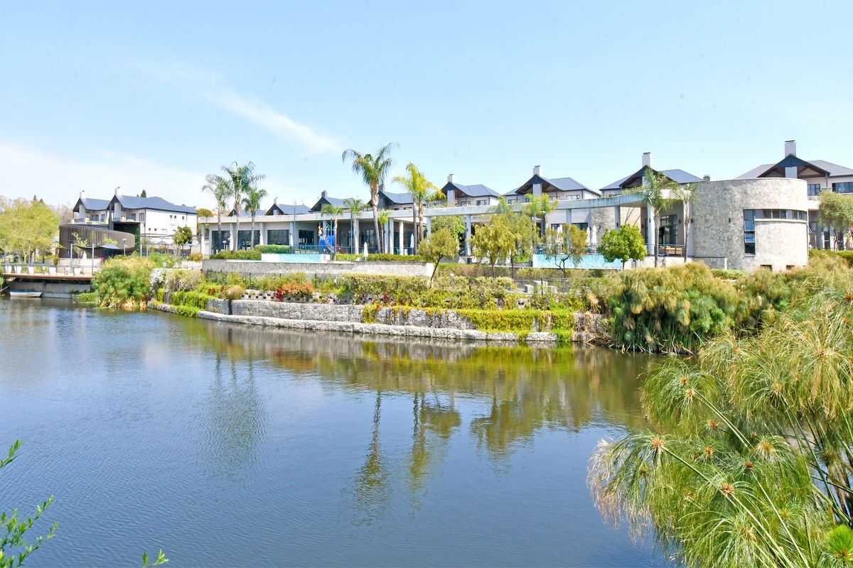 A scenic view of the apartment complex exterior featuring a landscaped garden, stone retaining walls, and a tranquil water feature.