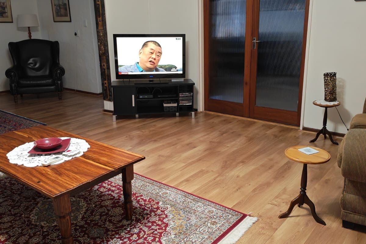 A spacious living room featuring wood-look laminate flooring and double timber-framed glass doors leading to an adjacent area.