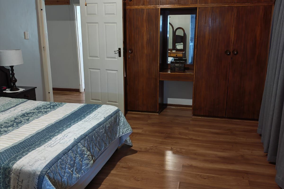 A bedroom featuring extensive built-in wooden cabinetry with an integrated vanity and wood-look laminate flooring.