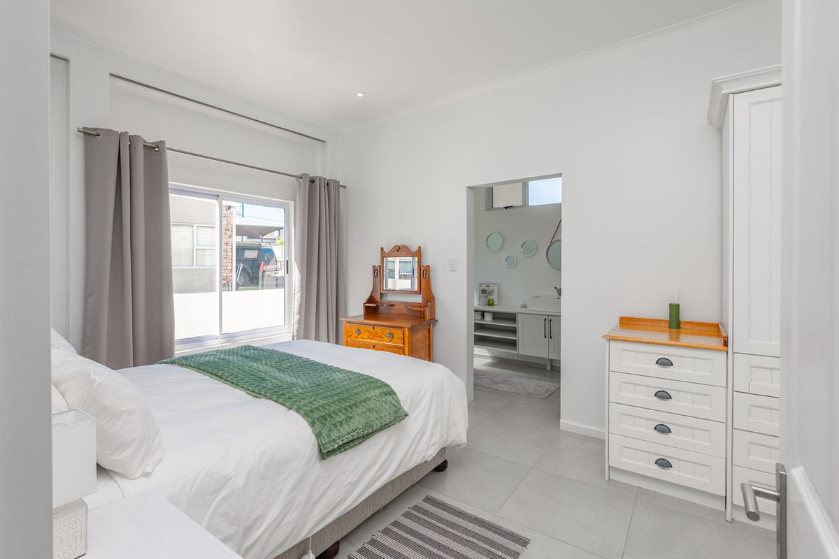 A bright, well-maintained bedroom featuring tiled flooring, a built-in wardrobe, and a sliding glass door providing natural light and access to the exterior.