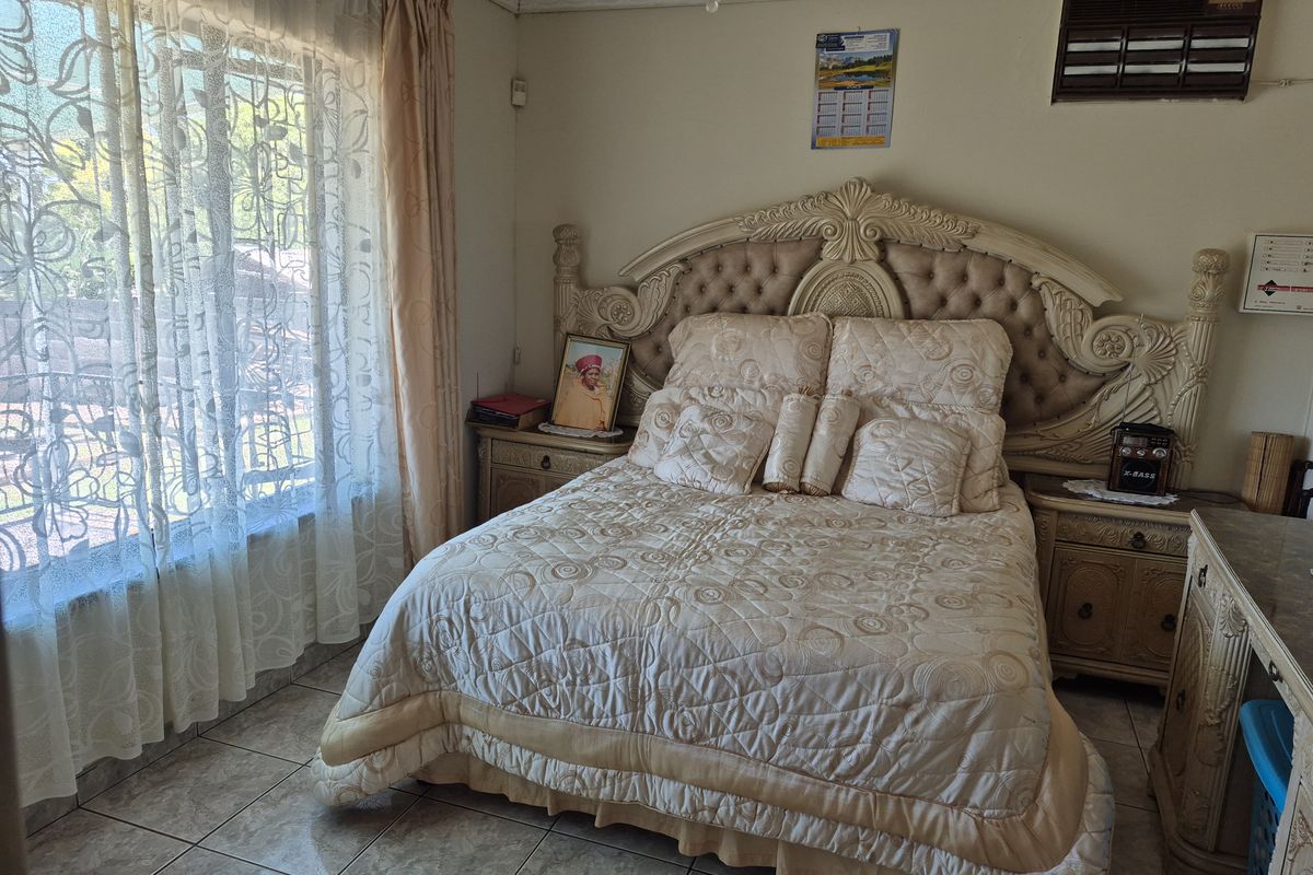A bedroom featuring tiled flooring, a built-in wall-mounted air conditioning unit, and large windows with security bars.