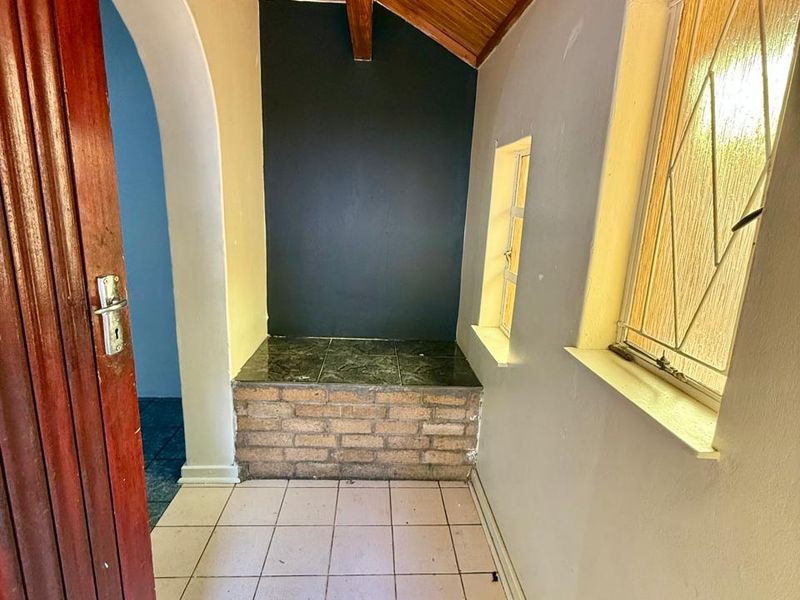 An entrance area featuring a timber-clad vaulted ceiling, tiled flooring, and a unique brick-based built-in bench with an arched transition to the interior.