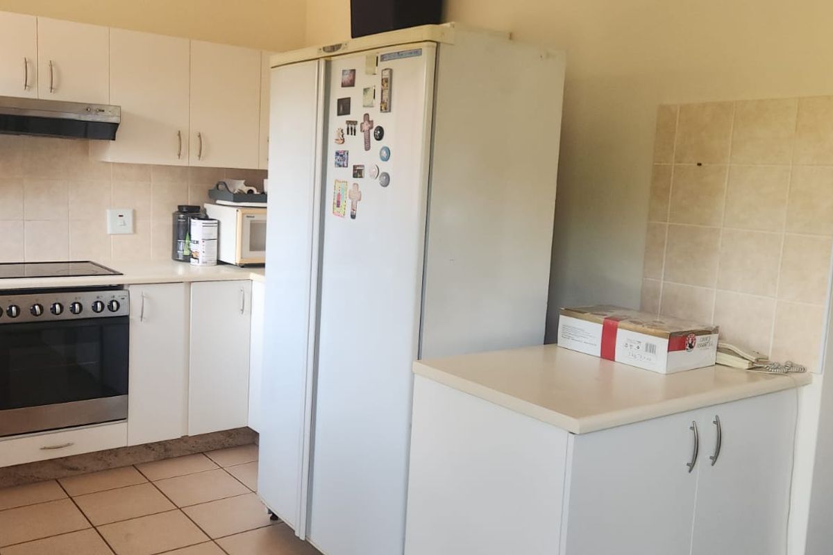 A functional kitchen featuring white cabinetry, tiled splashbacks, a built-in oven with hob, and an extractor fan.