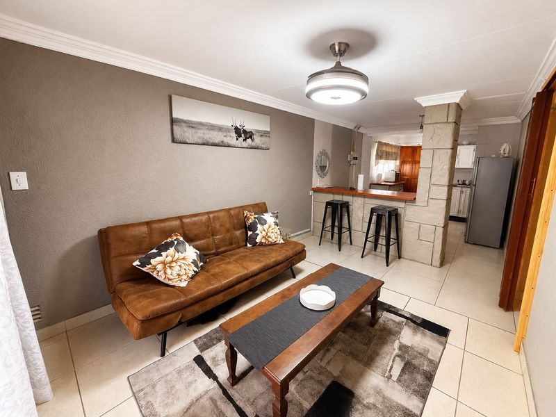 Open-plan living area featuring tiled flooring, a stone-clad pillar, and a breakfast bar connecting to the kitchen space.