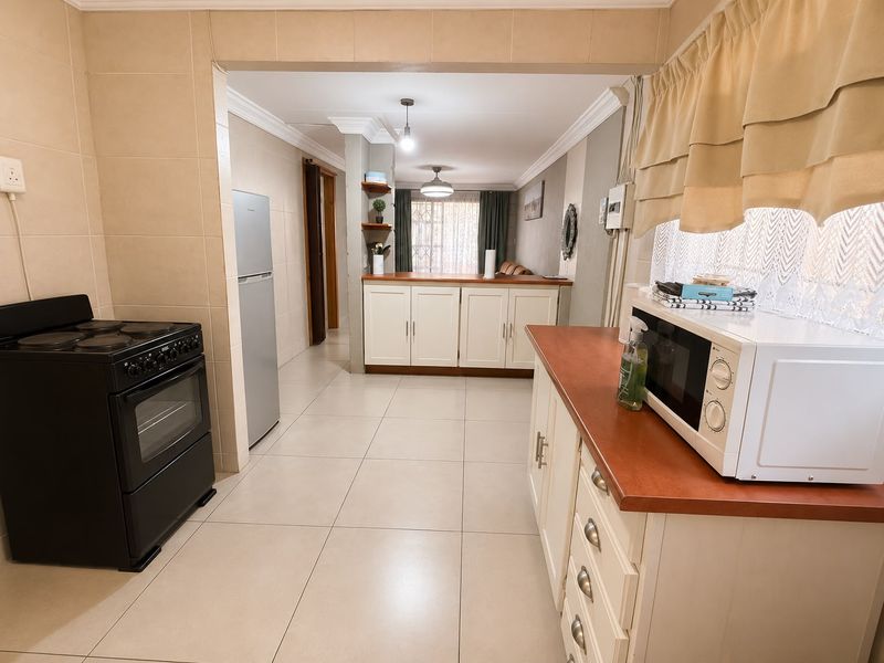 Open-plan kitchen and living area featuring tiled flooring, built-in cabinetry, and a functional layout connecting the cooking space to the lounge.