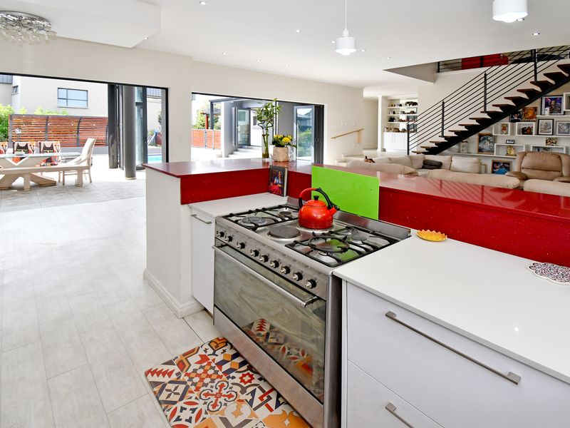Spacious open-plan kitchen and living area featuring a modern gas stove, stone countertops, and seamless flow to the outdoor patio through large sliding doors.