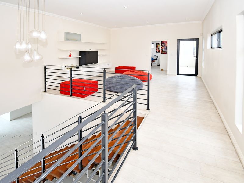 Spacious upper-level living area featuring a modern staircase with metal balustrades, built-in shelving, and contemporary tiled flooring.