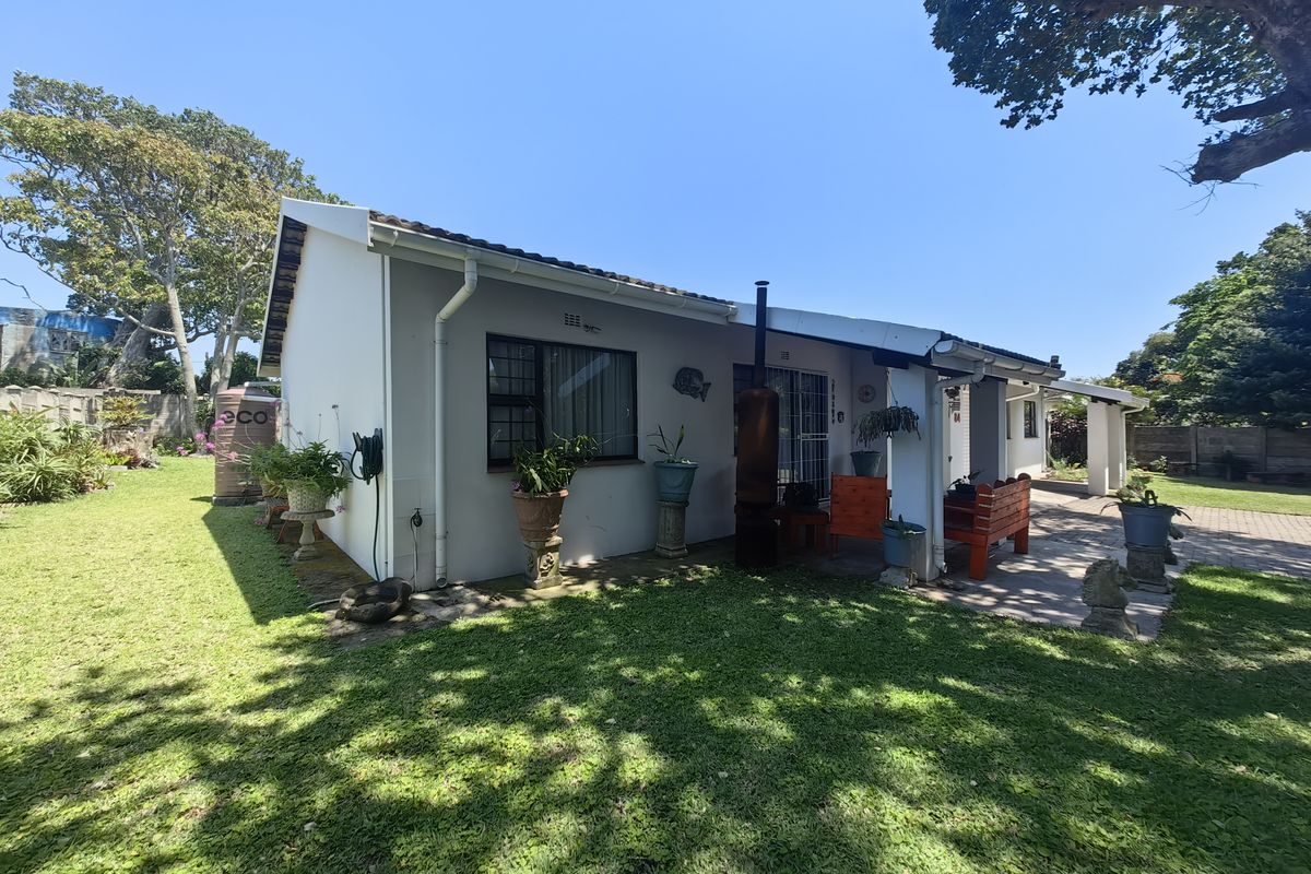 Rear view of the house featuring a covered patio, paved area, and established garden with a rainwater tank.