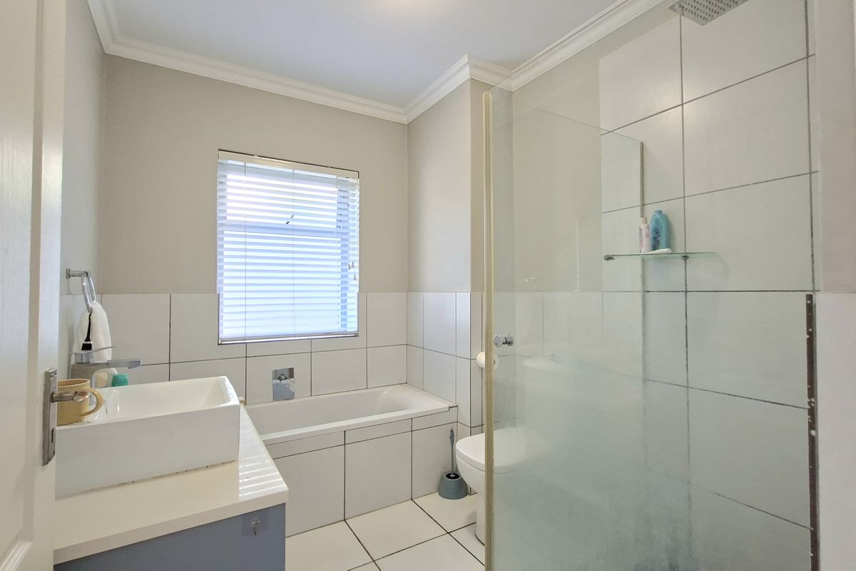 A clean, modern bathroom featuring a vessel sink vanity, a built-in bathtub, and a separate glass-enclosed shower with tiled finishes.