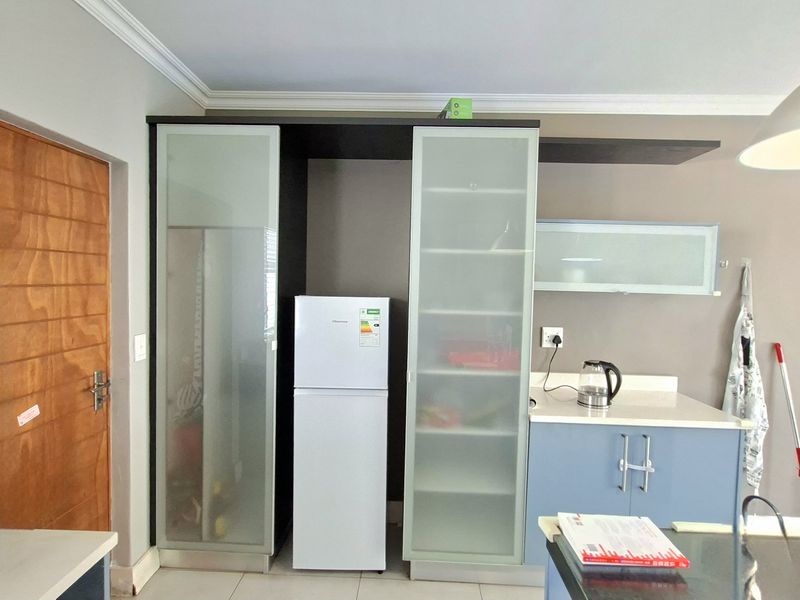 A functional kitchen area featuring built-in cabinetry with frosted glass doors, stone countertops, and tiled flooring.