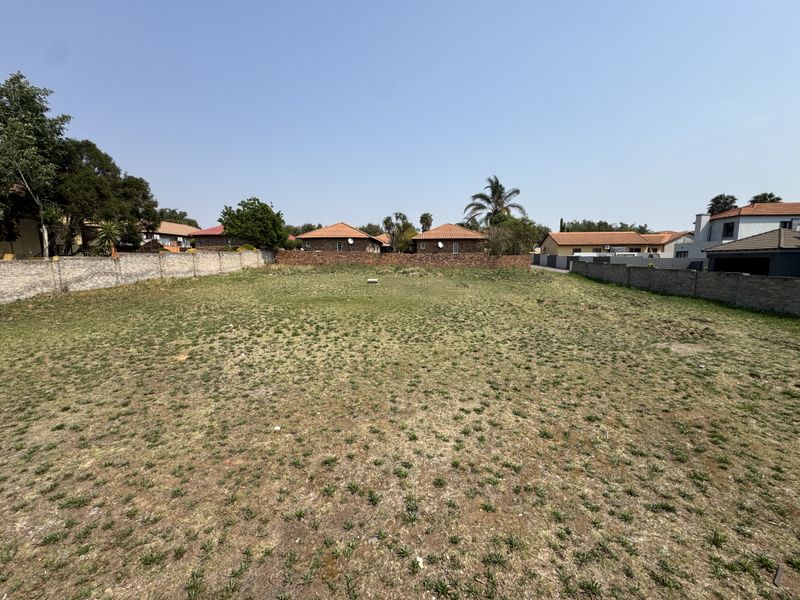 A vacant residential plot of land enclosed by perimeter brick walls, offering a clear space for potential development.