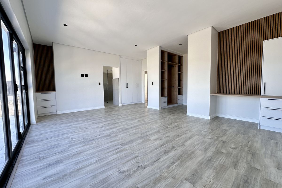 Spacious bedroom featuring modern wood-slat feature walls, built-in cabinetry, integrated shelving, and large sliding glass doors leading to the exterior.