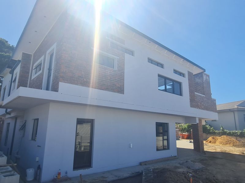Rear exterior view of a modern duet property featuring a combination of brick and plastered finishes with aluminium window frames under construction.