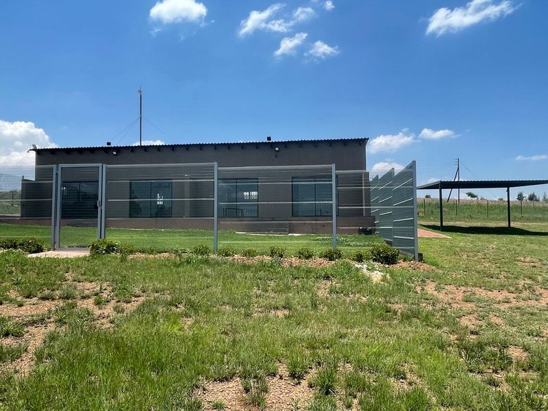 Rear view of the cottage featuring a fenced yard, sliding glass doors, and a detached metal carport structure on the property.