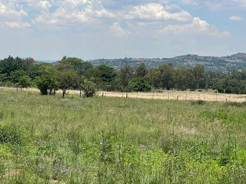 A scenic view of the surrounding landscape featuring open fields, mature trees, and distant hills under a cloudy sky.