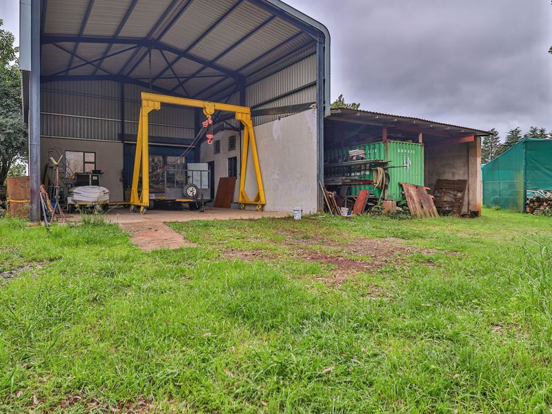 Large industrial-style utility shed featuring a steel portal frame, concrete flooring, and an integrated gantry crane, set within a spacious outdoor area.